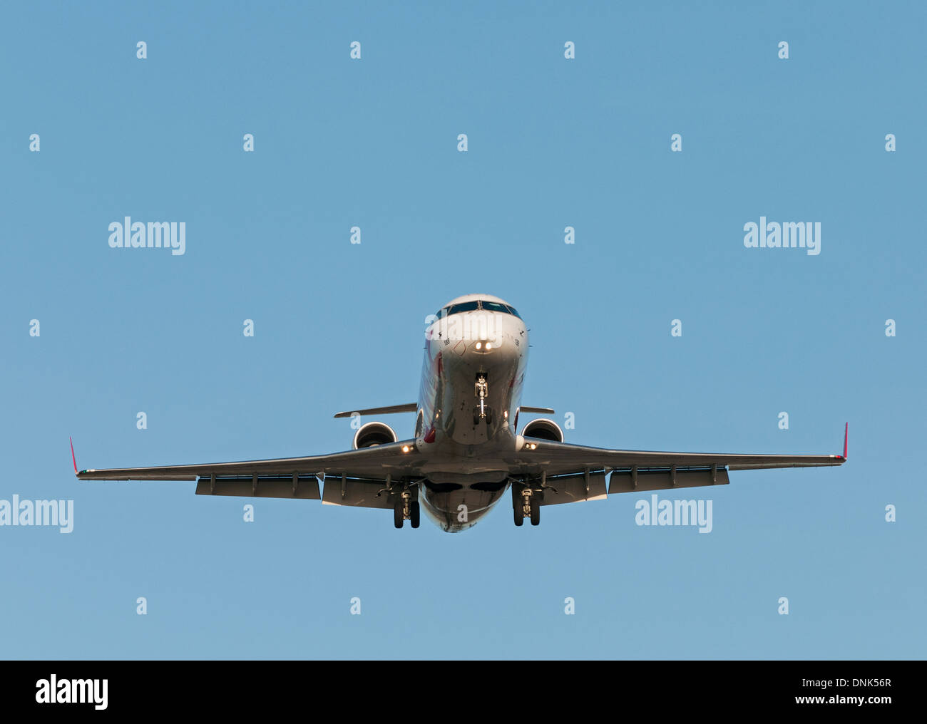 niedrigen Winkelkopf auf eine Bombardier CRJ-200LR Regionalverkehrsflugzeug im Endanflug zur Landung. Stockfoto