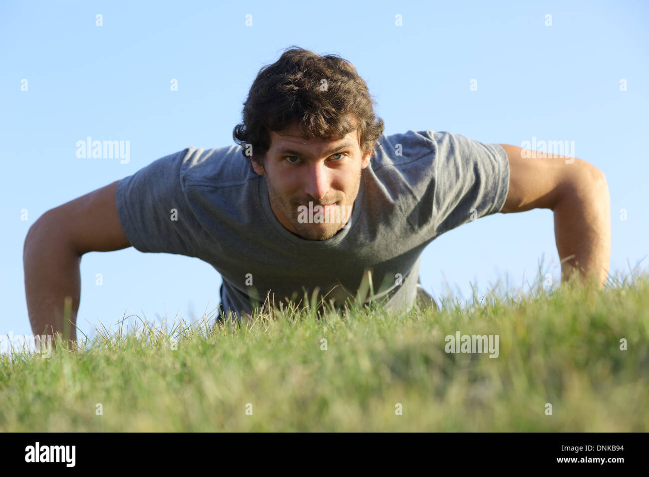 Nahaufnahme eines Mannes tun Liegestütze auf dem Rasen mit dem Horizont im Hintergrund Stockfoto