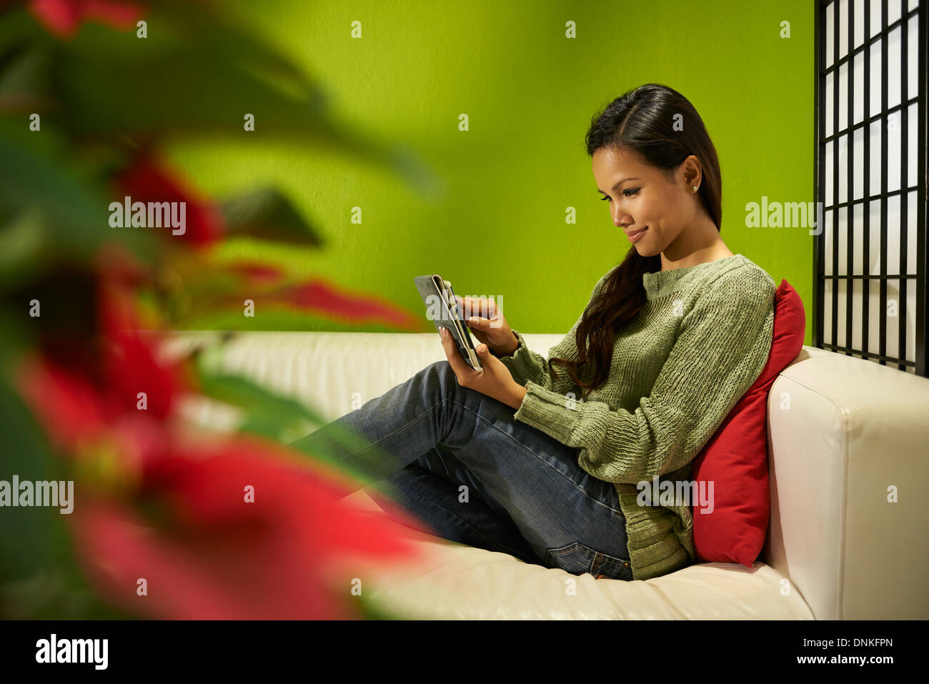 junge asiatische Frau, die mit dem Ipad zu Hause auf sofa Stockfoto