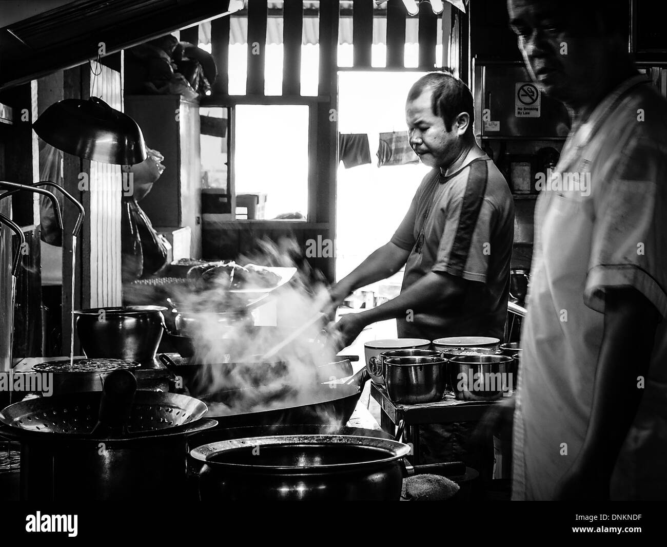 Der Meisterkoch Uhren seinen Lehrling Nudelgericht Char Kway Teow auf Pulau Ubin Island in Singapur zu kochen Stockfoto