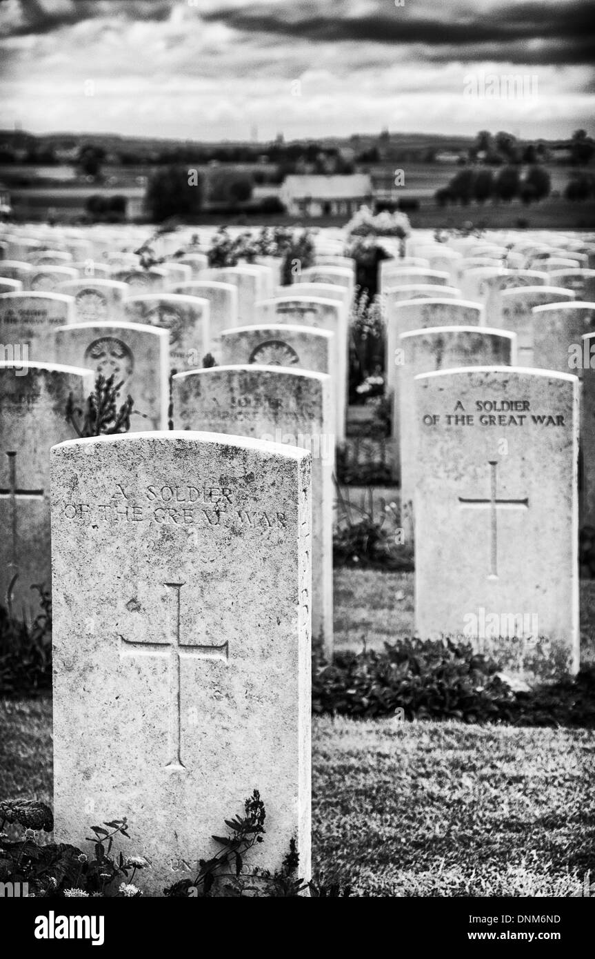 Grabsteine von Soldaten in Tyne Cot Soldatenfriedhof mit den Paschendaele Schlachtfeldern im Hintergrund Stockfoto