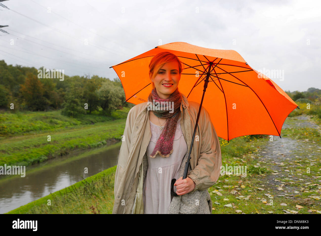 Oberhausen, Deutschland, geht eine junge Frau im Regen mit Regenschirm zu Fuß entlang der Emscher Stockfoto