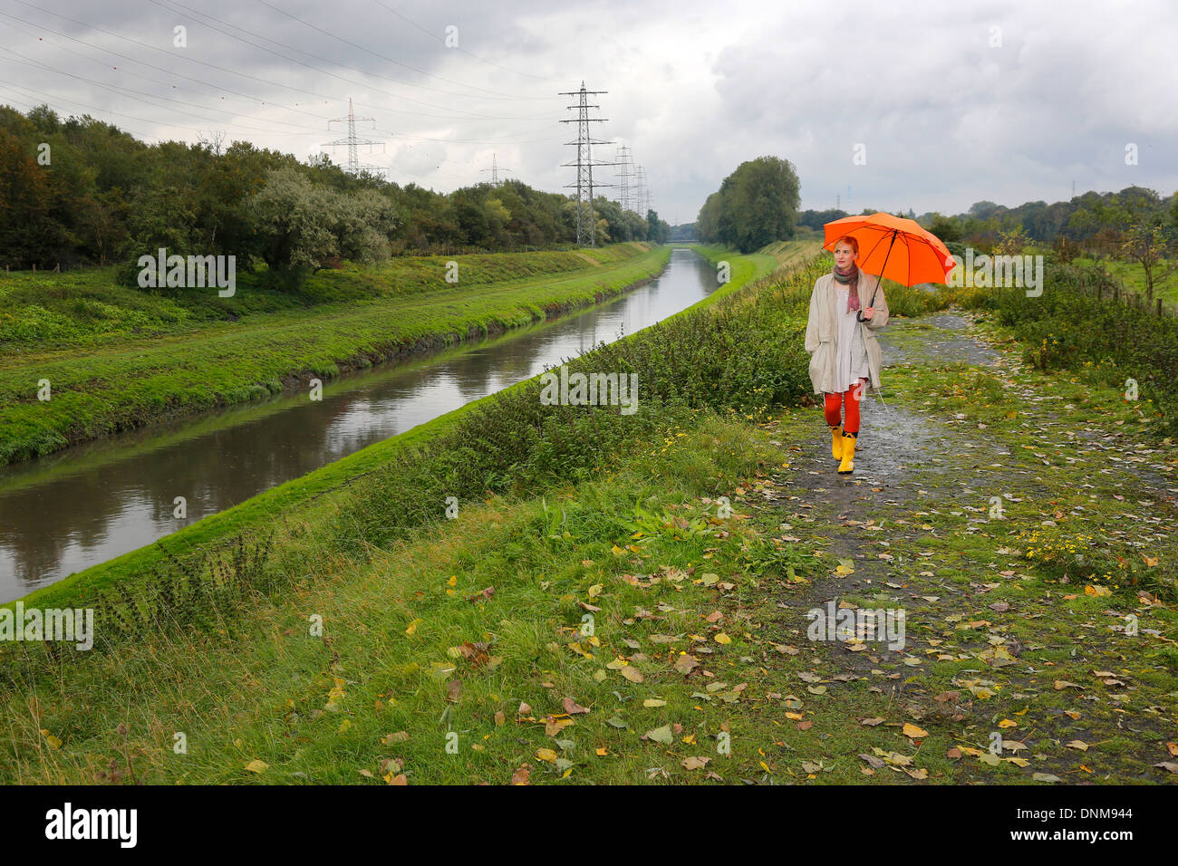 Oberhausen, Deutschland, geht eine junge Frau im Regen mit Regenschirm zu Fuß entlang der Emscher Stockfoto