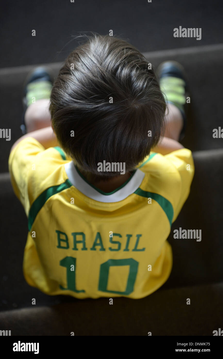 Berlin, Deutschland, ein Junge mit Brasilien Fußball Jersey sitzt auf einer Treppe und pouts Stockfoto