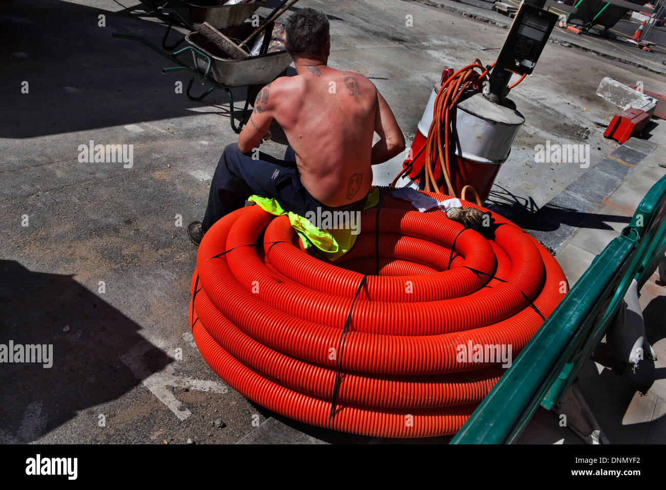 Mann sitzt auf Verkabelung für Straßenbauarbeiten am Russell Square, London Stockfoto