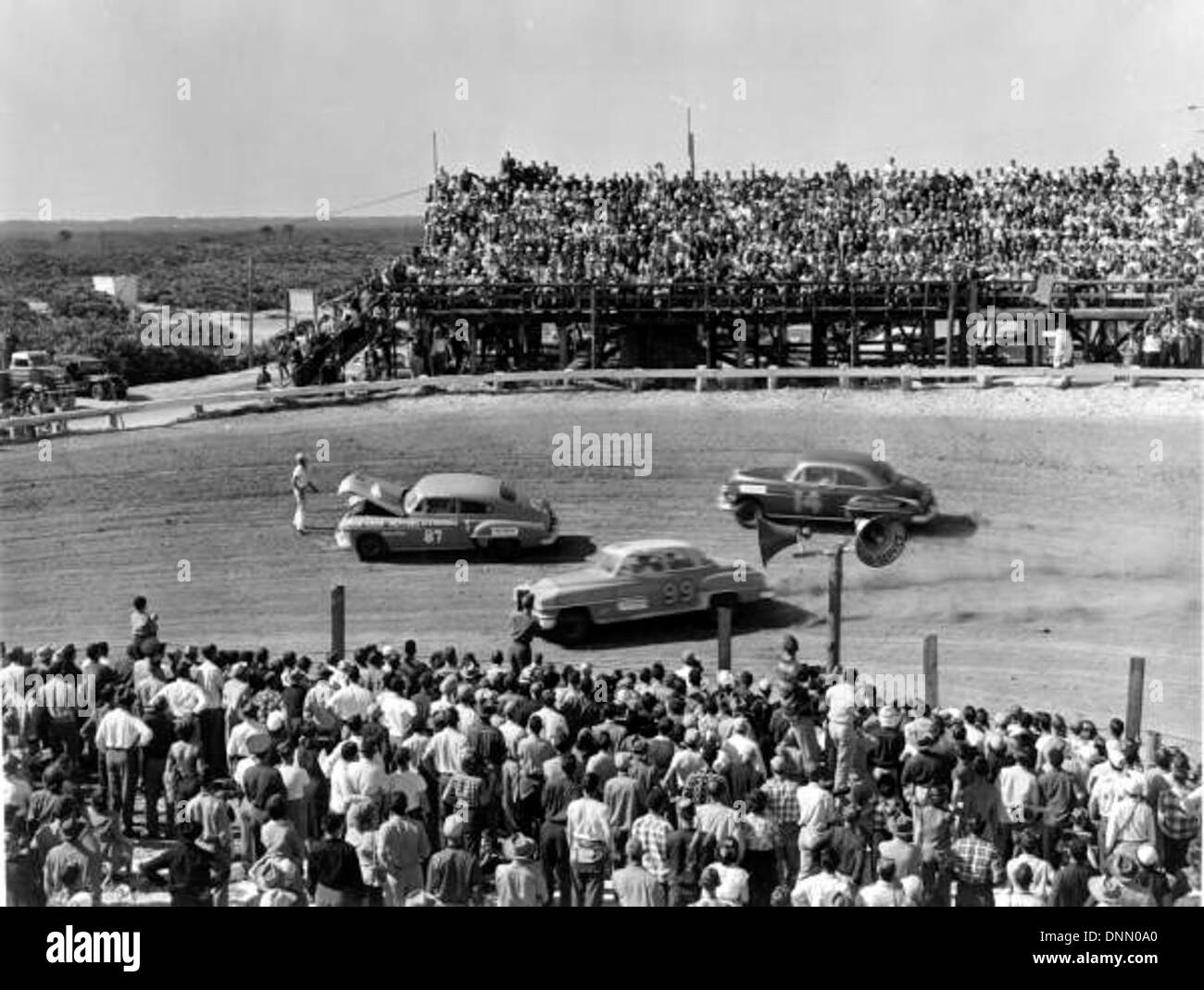 Dieses dramatische Bild zeigt Fahrer, die in den 1950er Jahren bei einem Rennen in Daytona Beach, Florida, einem festgefahrenen Rennwagen nur knapp entgehen Es ist Teil der Daytona Beach Department of Commerce Collection. Stockfoto