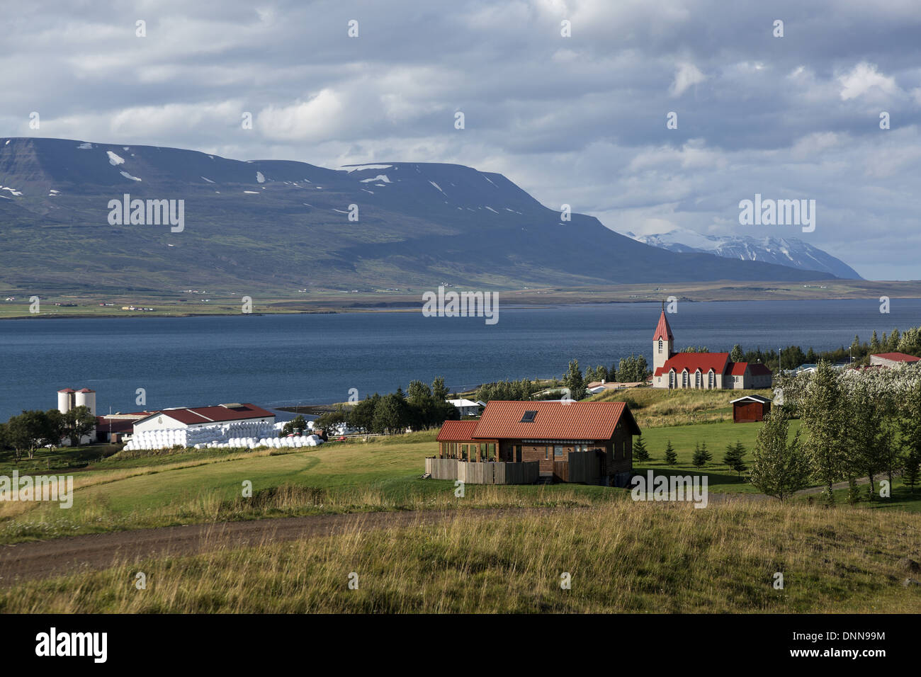 Eine isländische Dorf zeigt die Kirche Farm des Svalbaro auf der Ostseite des Eyjafjordur, mit Fjord in Nord-Ost-Island Stockfoto