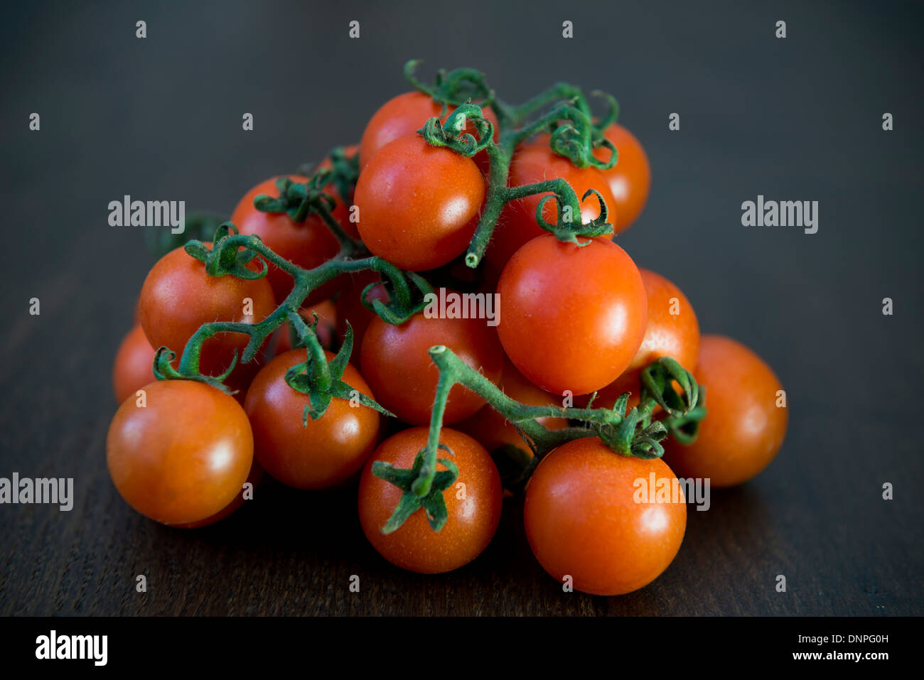 Cherry-Tomaten auf einem dunklen Holzbrett Stockfoto