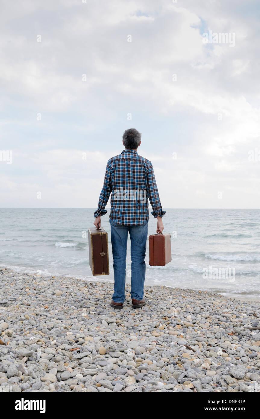 Rückseite des Mann mit Koffer auf felsigen Strand, Frontignan, Frankreich Stockfoto