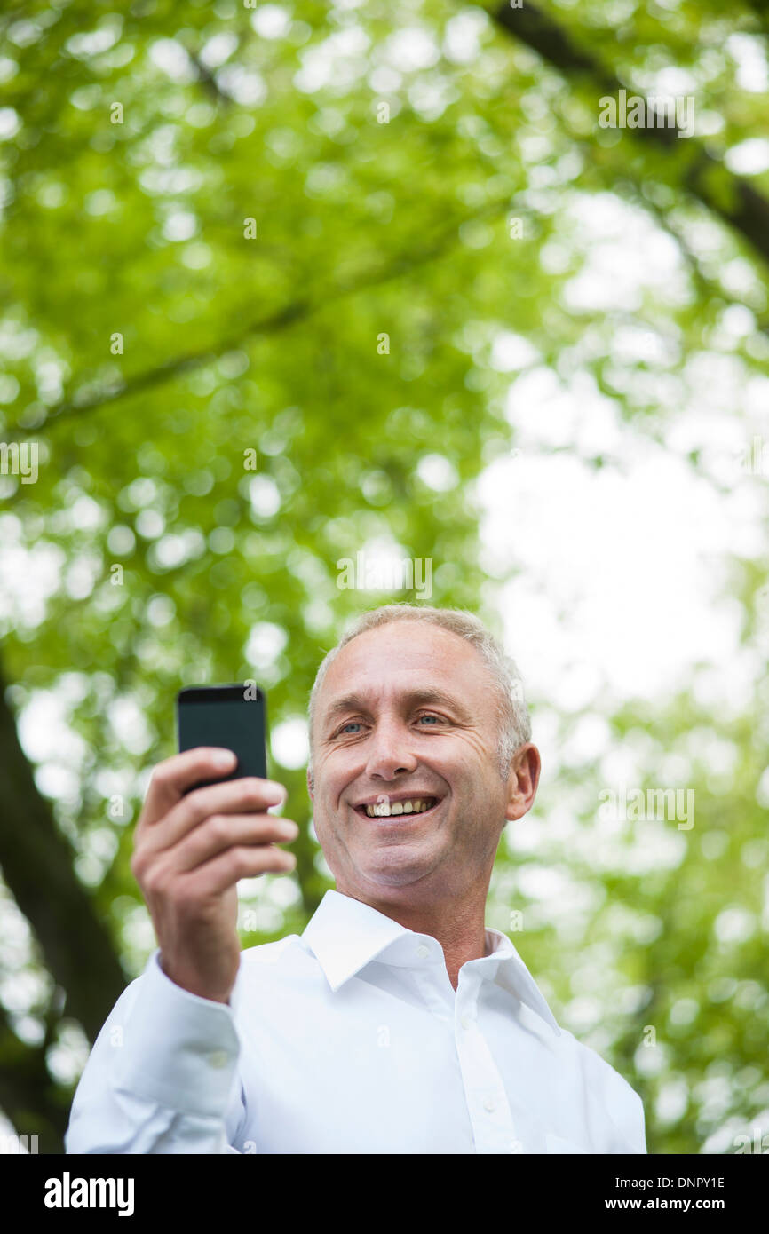 Nahaufnahme des reifen Mannes Blick auf Smartphone im Park, Mannheim, Deutschland Stockfoto