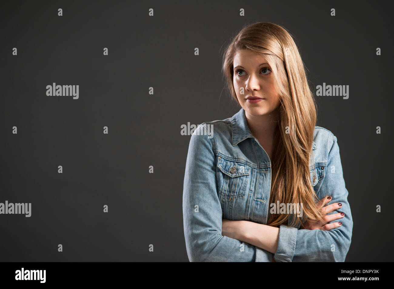 Porträt der jungen Frau mit langen, blonden Haaren, Studio gedreht auf grauem Hintergrund Stockfoto