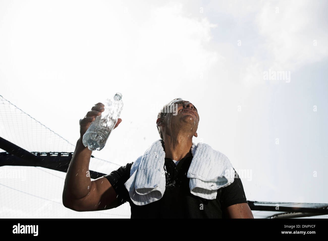 Reifer Mann mit Handtuch um den Hals, halten Sie die Flasche Wasser und blickte zu Himmel, Deutschland Stockfoto