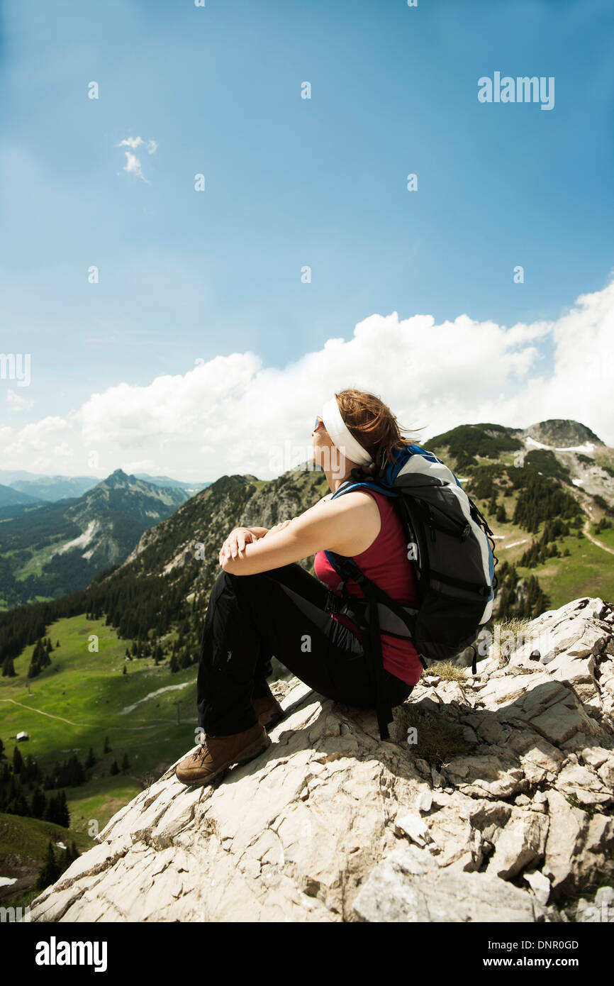 Reife Frau sitzen auf Klippe, Wandern in Bergen, Tannheimer Tal, Österreich Stockfoto