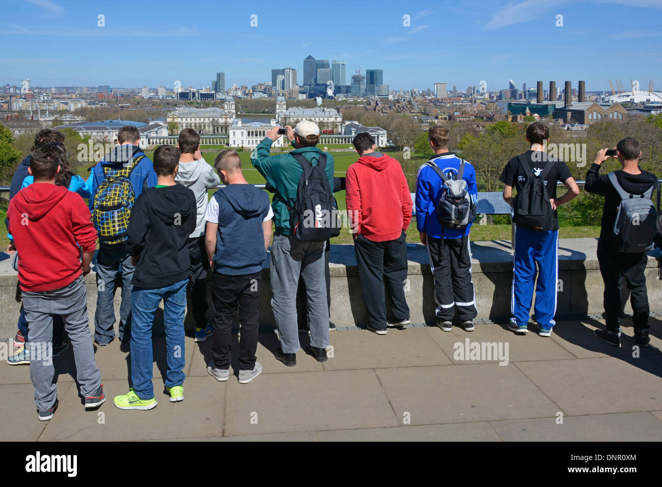 Gruppe von Jugendlichen Jungen Studenten auf Bildungsreise Greenwich Park & Hilltop Observatory mit Blick auf die Skyline von Canary Wharf London, England, Großbritannien Stockfoto