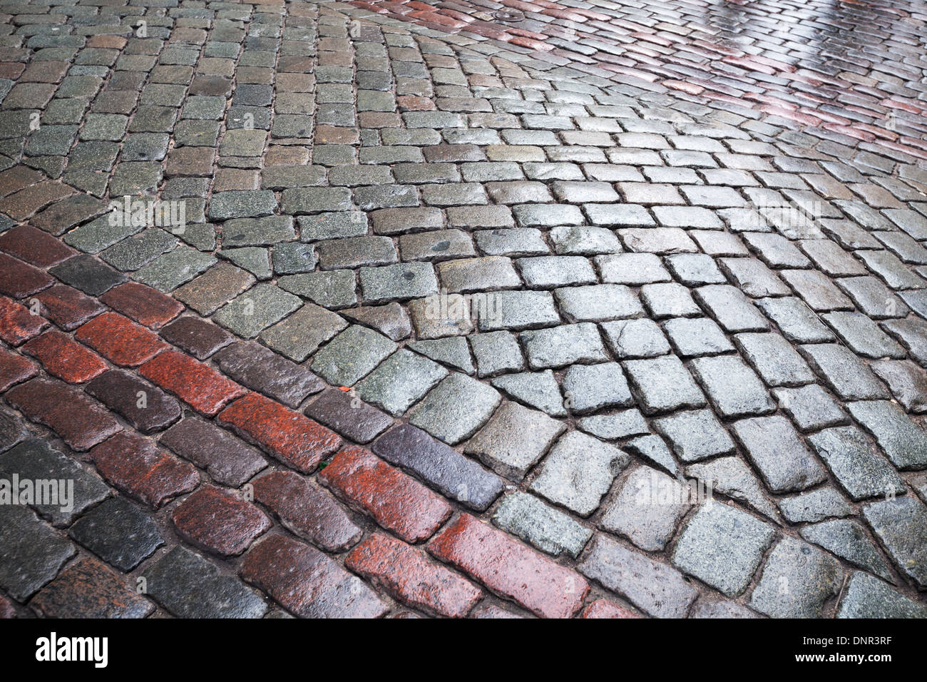 Hintergrundtextur von nassen Granit Kopfsteinpflaster städtische Straße Stockfoto