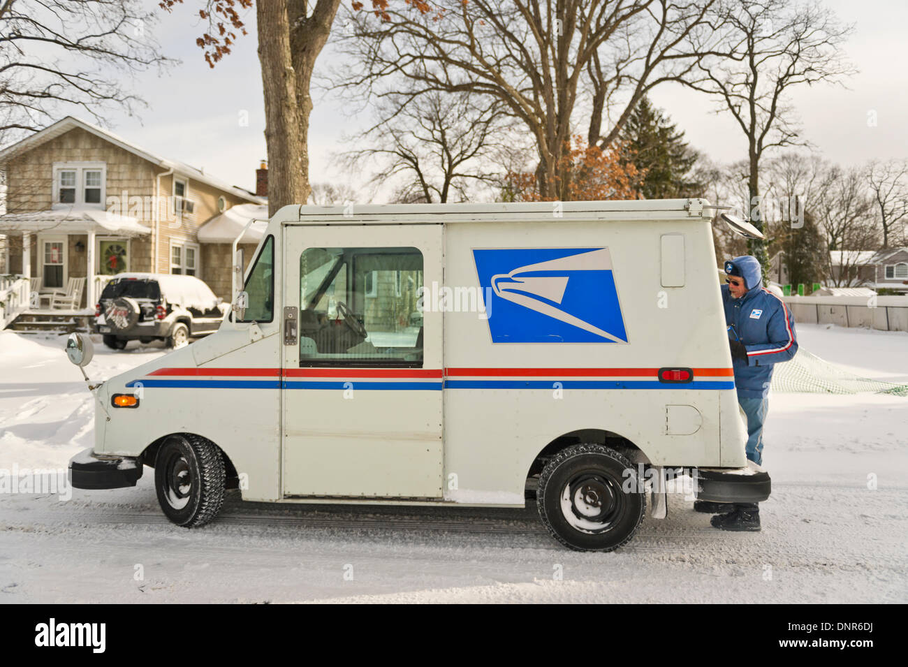 Merrick, New York, USA 3. Januar 2014. Ein United States Postal Service USPS LKW und Postboten zustellen, wie eine gefährliche Tieffrieren siedelt sich in, nach ein Schneesturm 6-12 Zoll Schnee auf Long Island abgeladen. Der Temperaturbereich ist 13 bis 18 Grad Celsius (-11 °-8 ° Celsius), mit Wind Böen bis zu 45 km/h. Wind Chill Faktoren machen es zwischen 5 ° C bis-10 ° F (-15 ° bis-23 ° C), mit Rekordtief bei Nacht erwartet. Bildnachweis: Ann E Parry/Alamy Live-Nachrichten Stockfoto
