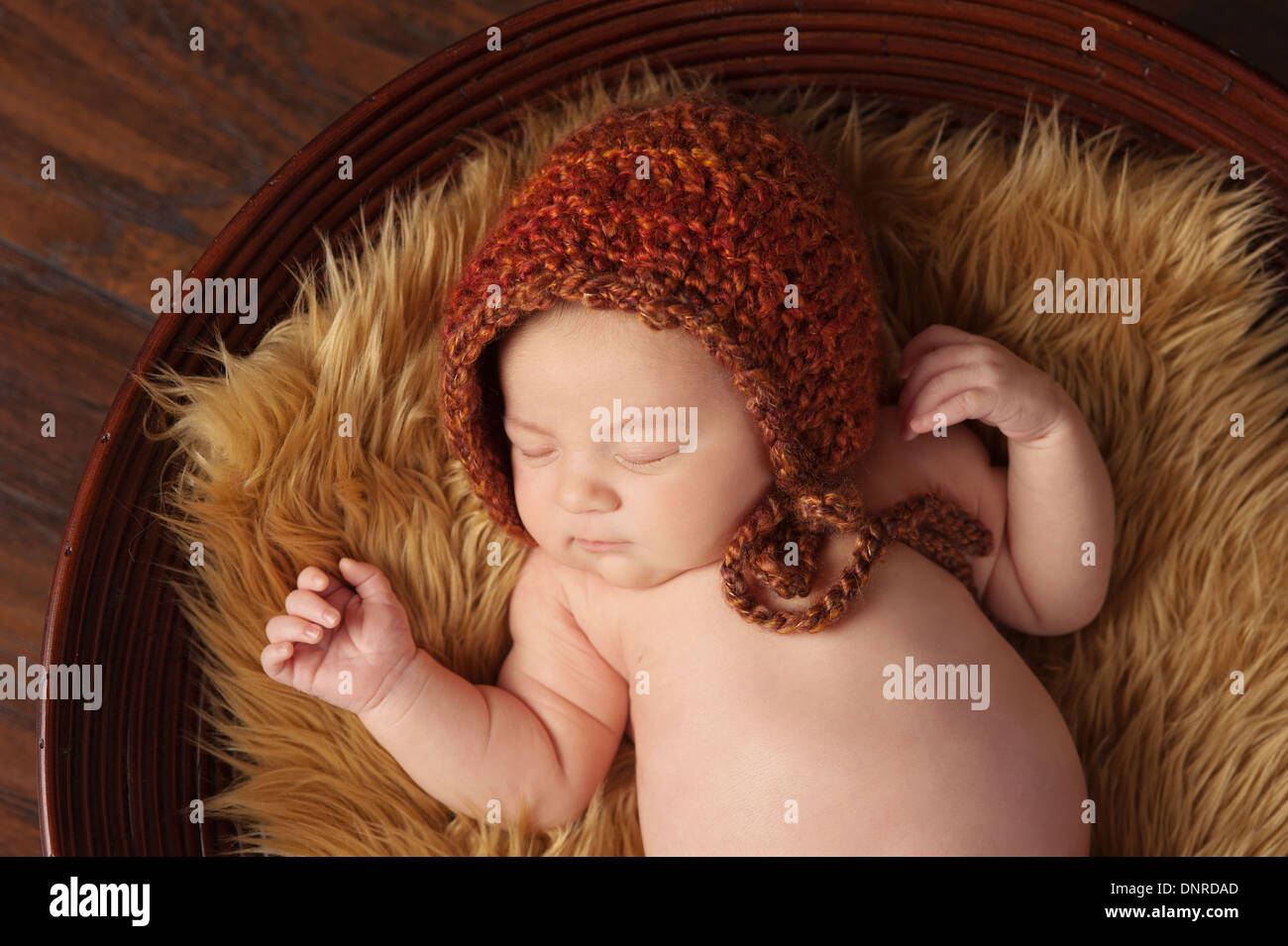 Ein Portrait eines schlafenden, zwei Wochen alten neugeborenen Mädchens tragen eine gehäkelte Mütze in den Farben des Herbstes. Stockfoto