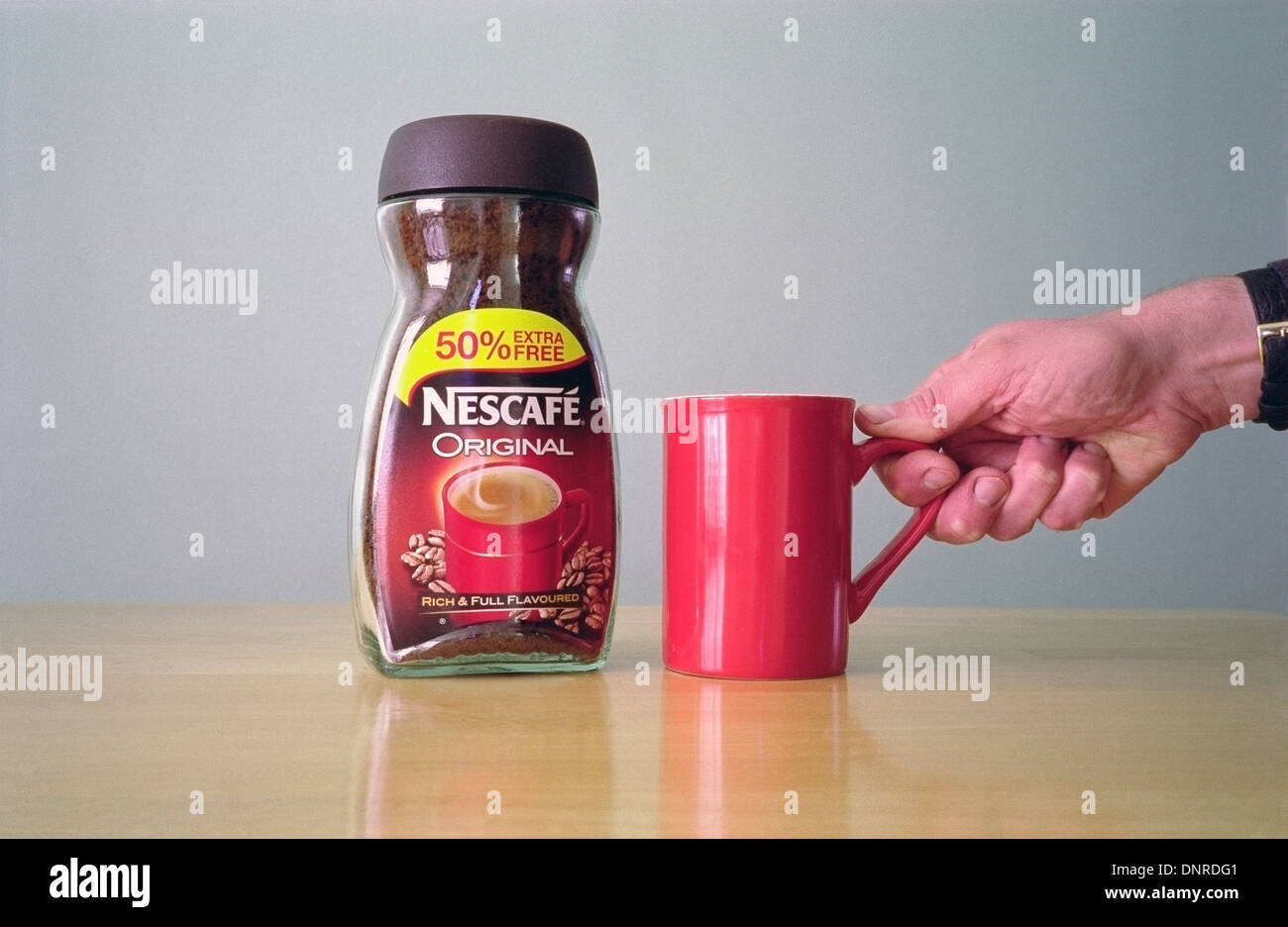 Glas mit Original Nescafe Instant-Kaffee und kaukasischen Mann Hand hob einen roten Becher Modell veröffentlicht Stockfoto