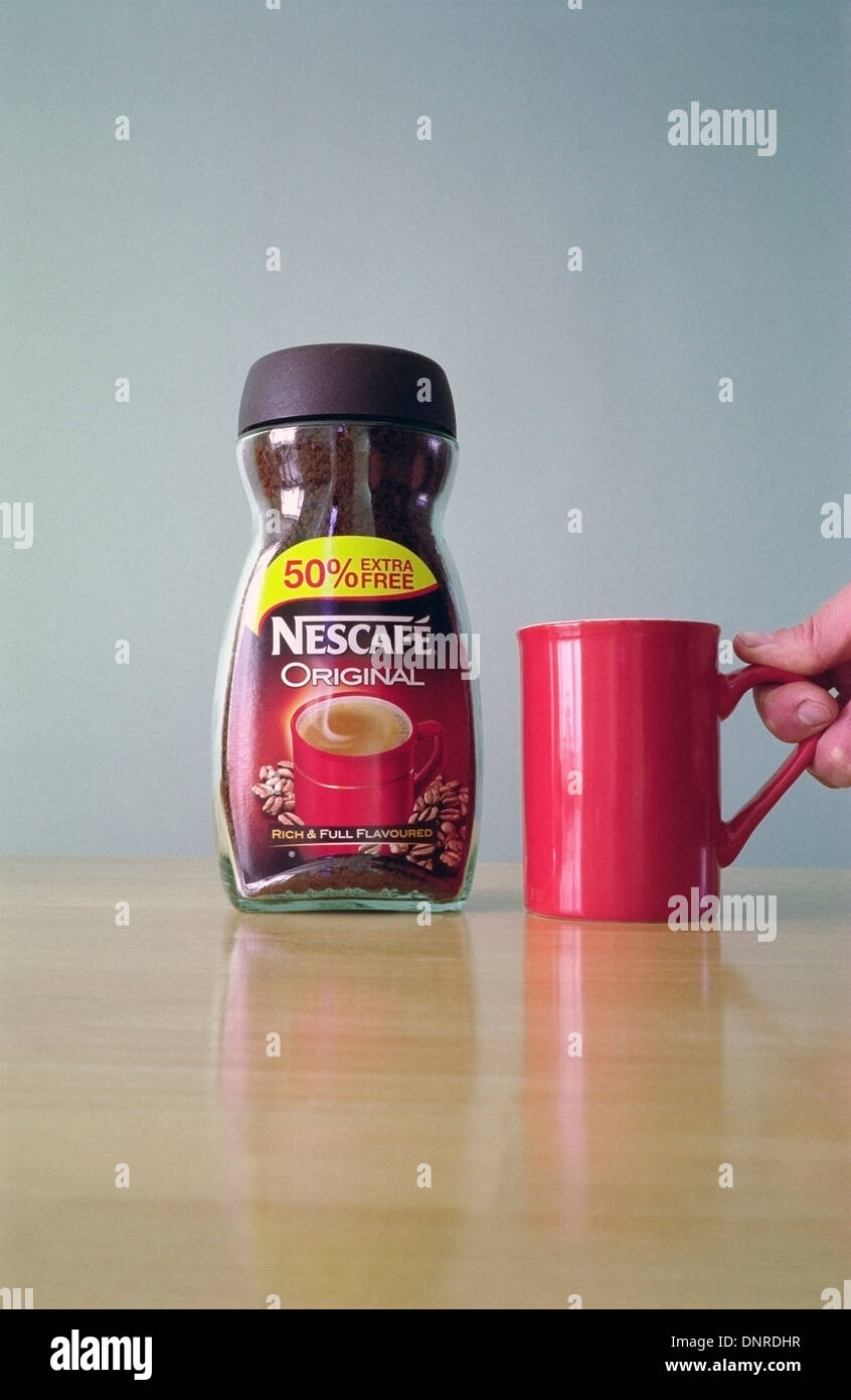 Glas mit Original Nescafe Instant-Kaffee und kaukasischen Mann Hand hob einen roten Becher Modell veröffentlicht Stockfoto