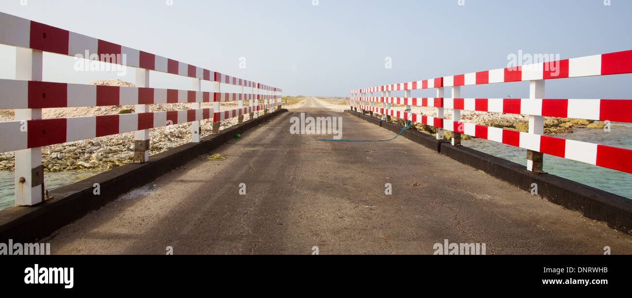 Eine Brücke in Bonaire mit roten und weißen Geländer entweder seitlich und der Straße in der Ferne scheint ewig so weitergehen. Stockfoto