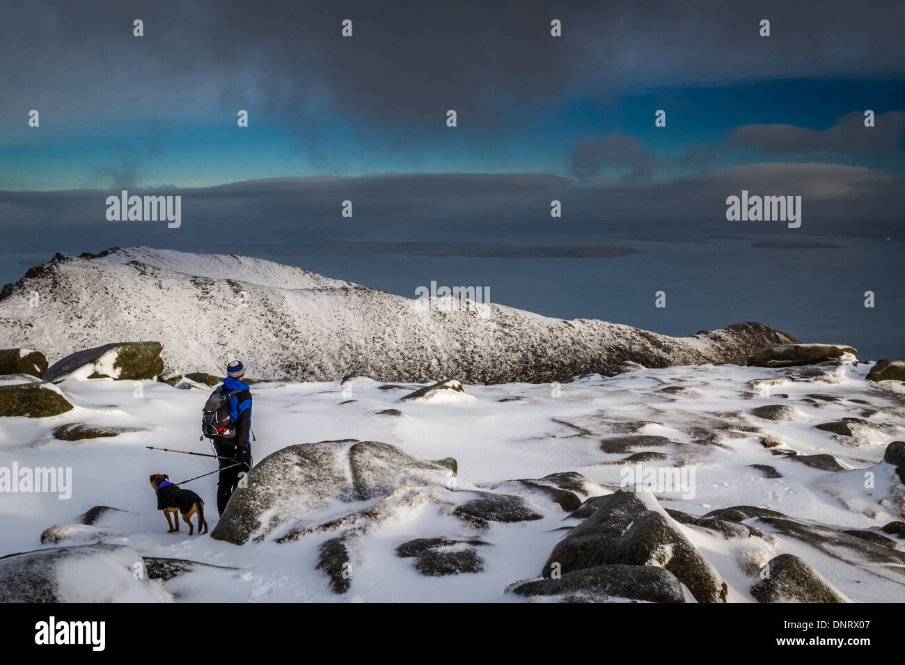 Person mit Hund im Schnee auf Ziege fiel die Berge im Winter, Isle of Arran Stockfoto