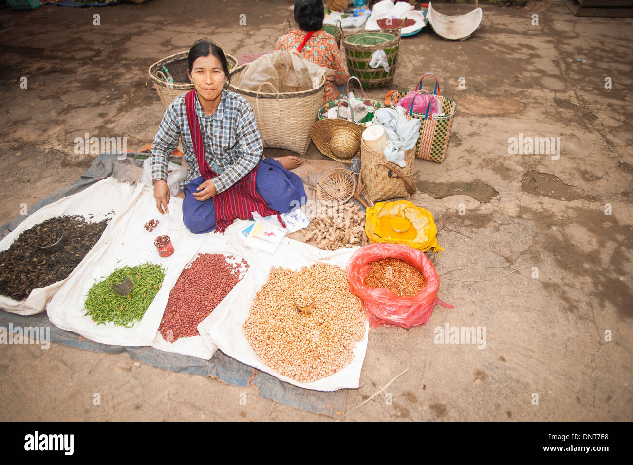 Asiatischen Märkten, sitzt eine Frau hinter ihr Angebot von Samen und Gewürzen auf Boden Blättern und in Säcken auf einem traditionellen Markt zu verbreiten Stockfoto