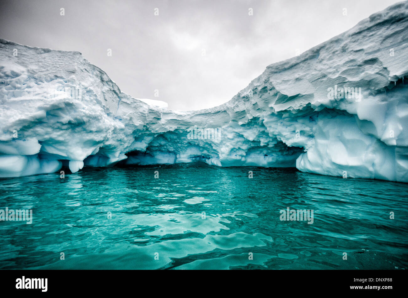 Antarktis - ein Schuss aus einer kleinen Abdeckung durch einen Eisberg geschaffen, mit dem Grün der Unterwasser Segment des Eisbergs im Vordergrund. Curtis Bucht, Antarktis. Stockfoto