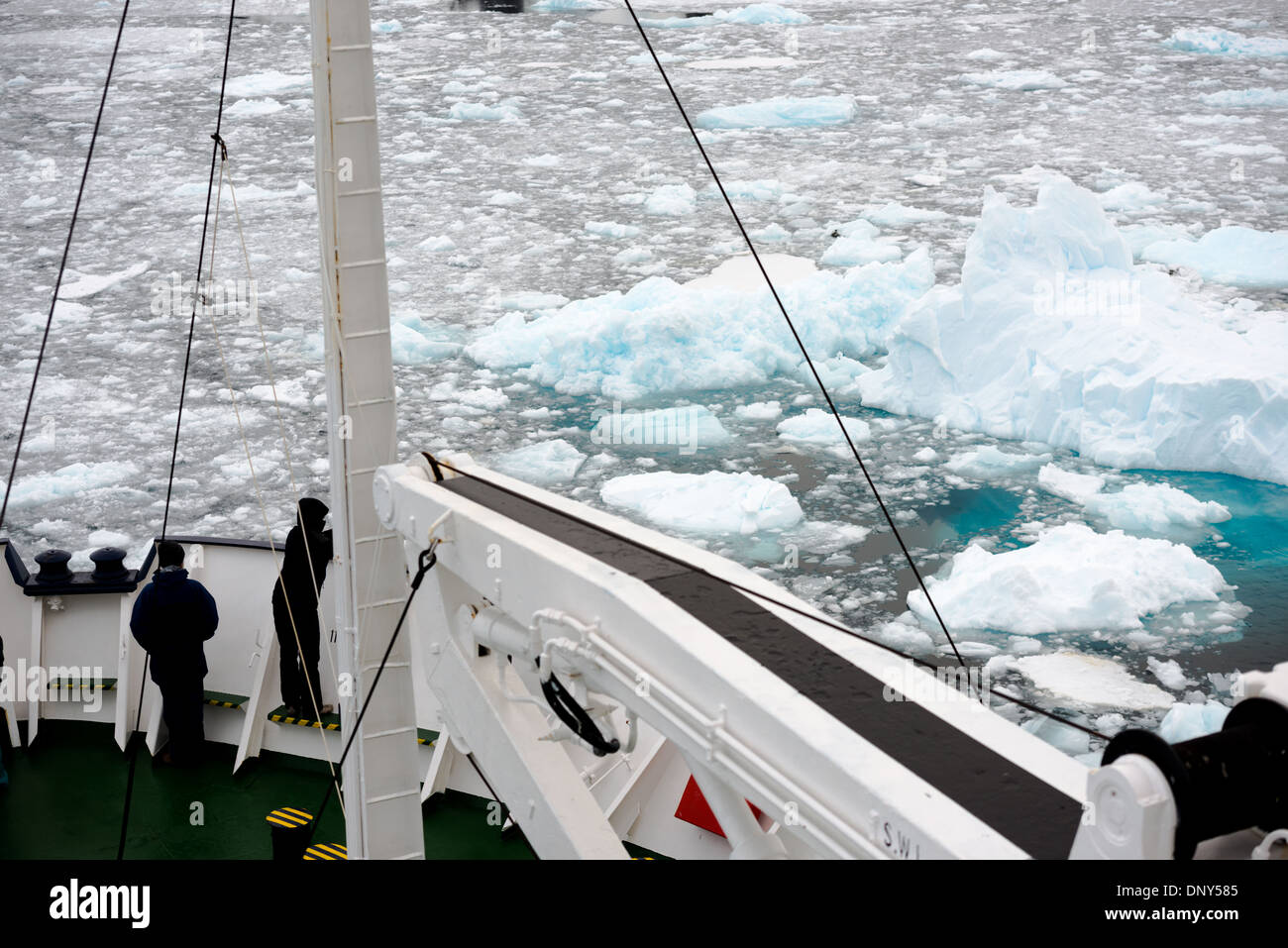 Antarktis - Fahrgäste stehen auf dem Bug eines ice-gestärkt Kreuzfahrtschiff, wie es navigiert der Lemaire Kanal mit der Oberfläche des Wassers mit Glatteis und brash Eis bedeckt. Die Lemaire Kanal wird manchmal auch als "Kodak Lücke' in einem Kopfnicken zu seiner berühmt malerische Aussicht bezeichnet. Stockfoto