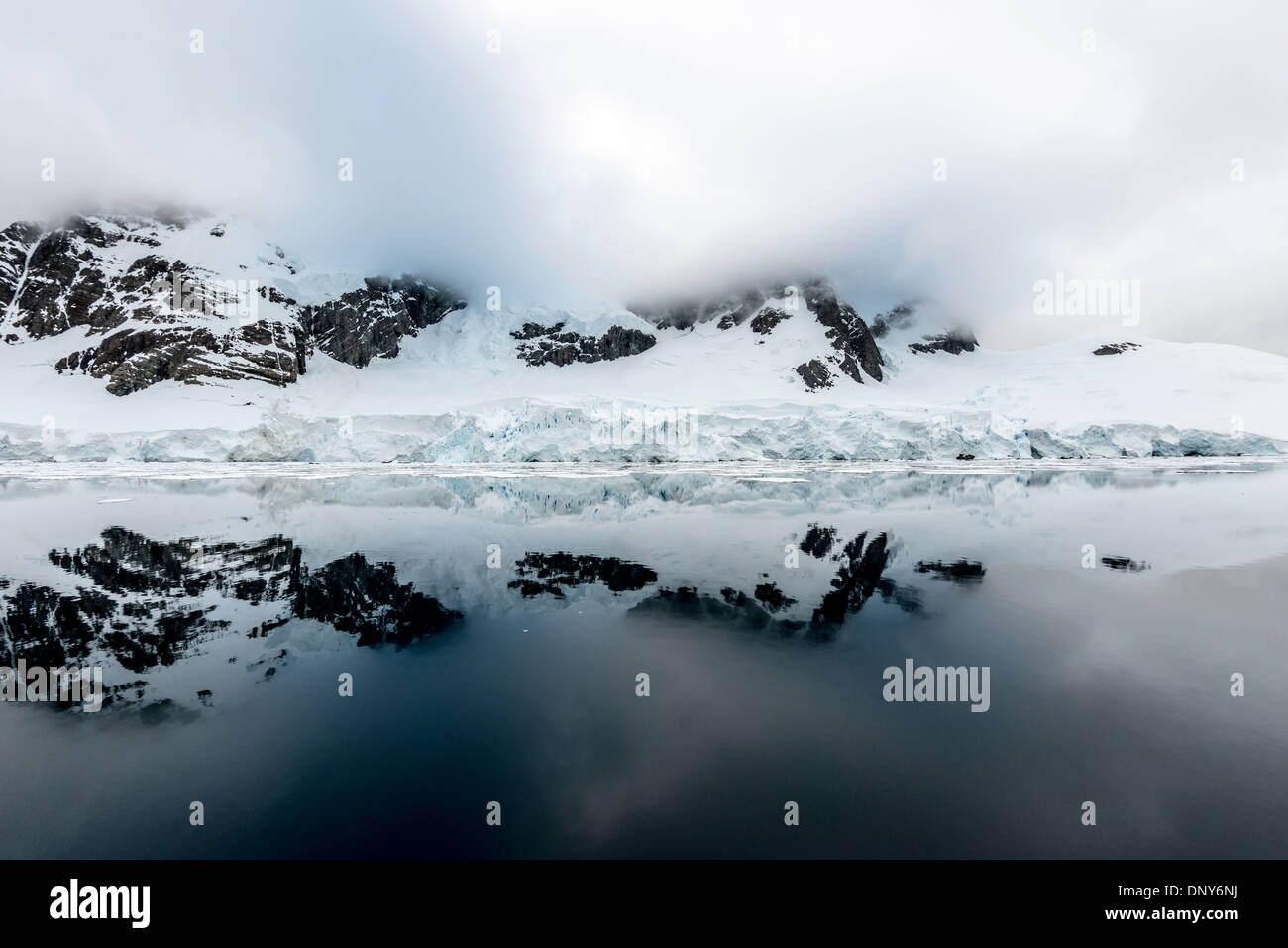 Lemaire Channel Reflections Antarktis // LEMAIRE CHANNEL, Antarktis — perfekte spiegelähnliche Reflexionen der Berge und Klippen am Glandaz Point auf Booth Island schaffen eine symmetrische Szene in den ungewöhnlich ruhigen Gewässern. Diese glasartigen Bedingungen im Lemaire-Kanal, auch „Kodak Gap“ genannt, sind selten in dieser typisch windgepeitschten Region der Antarktischen Halbinsel. Die stillen Gewässer bilden einen natürlichen Spiegel der dramatischen antarktischen Landschaft. Stockfoto
