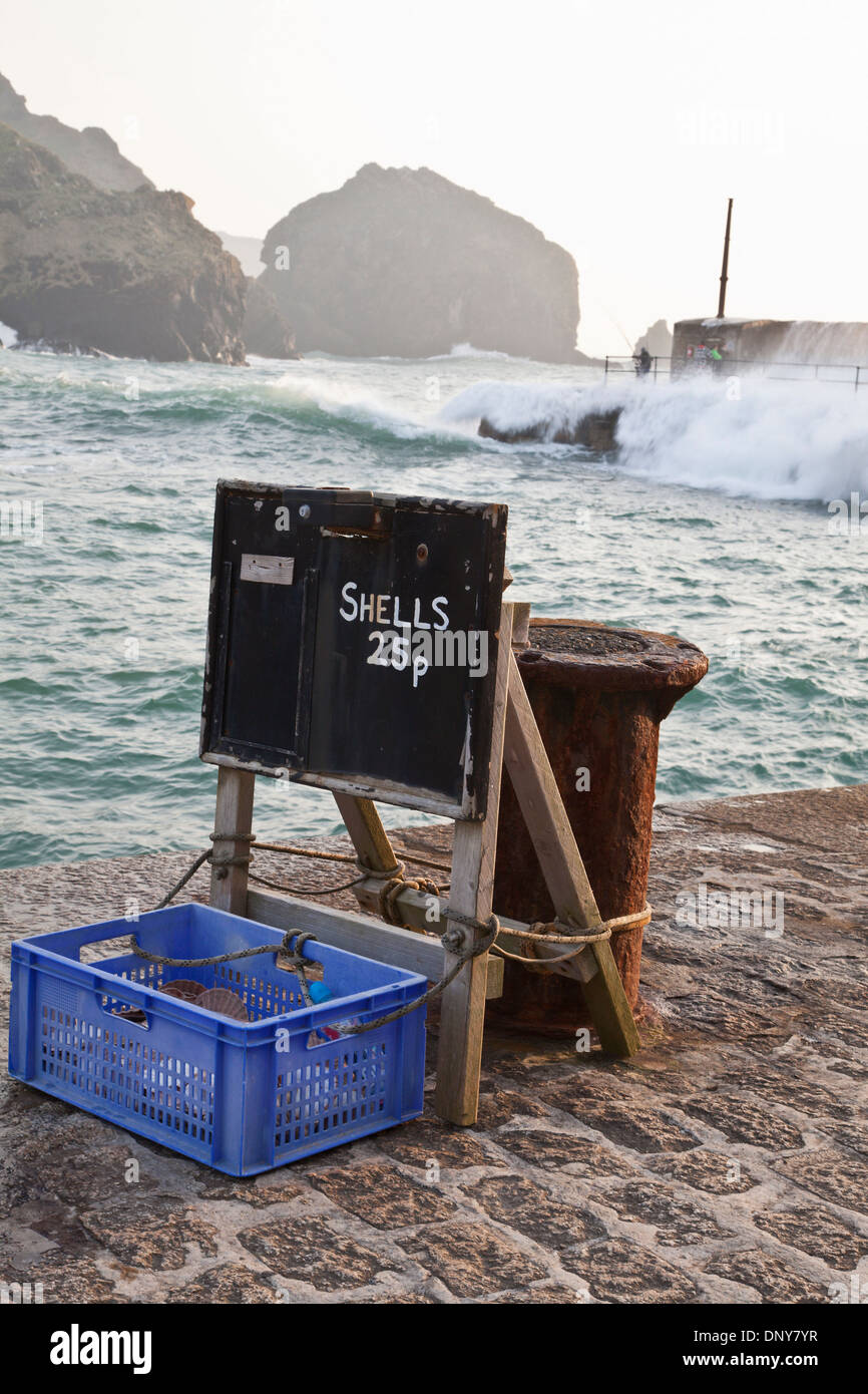 Mullion Cove Hafen, Halbinsel Lizard, Cornwall. Raue Brandung über Menschen auf der Hafenmauer hinter Stockfoto