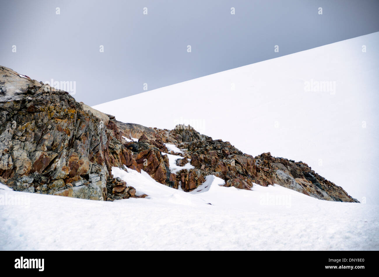 Antarktis - Gezackte exponierten Felsen ragen aus dem tiefen Schnee auf Petermann Island in der Antarktis. Stockfoto