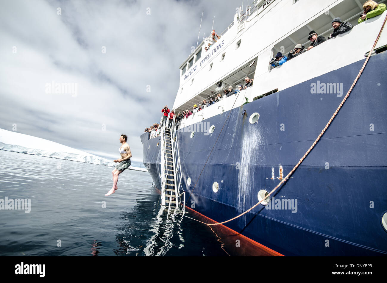 Antarktis - Passagiere nehmen die Polar Plunge, tauchen in die eiskalten Wasser von der Seite des Schiffes in der Nähe von Melchior Insel an der Westküste der Antarktischen Halbinsel. Die Polar Pioneer ist ein russisches Eis gestärkt Schiff durch die australische Firma Aurora Expeditions betrieben. Stockfoto