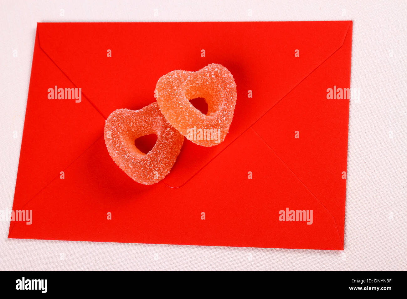 Zwei Herzen aus Zucker Bonbons auf roten Umschlag, Nahaufnahme Stockfoto