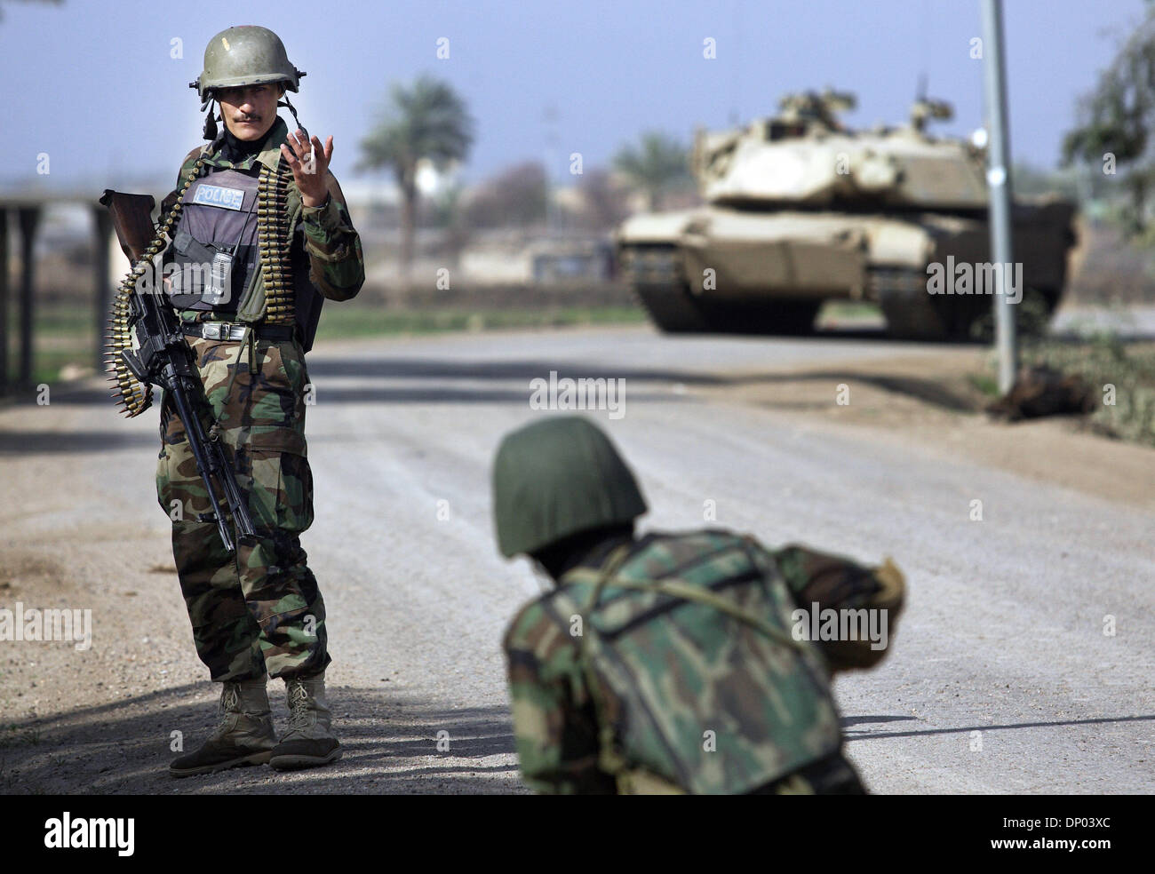 28. Februar 2006; In der Nähe von Ar-Ramadi, Al-Anbar, Irak; Eine irakische Polizei-Sonderkommandos aus dem 2. Bataillon 2. Brigade, auch bekannt als "Wolf Brigade" Gespräche zu einem Kameraden (gesichert durch eine amerikanische M1A1 Abrams-Panzer im Hintergrund) in einer ländlichen Gegend nur nördlich der irakischen Stadt Ar Ramadi am 28. Februar 2006. Die irakische Polizei waren auf einer gemeinsamen Mission mit Soldaten der 101. airbour Stockfoto