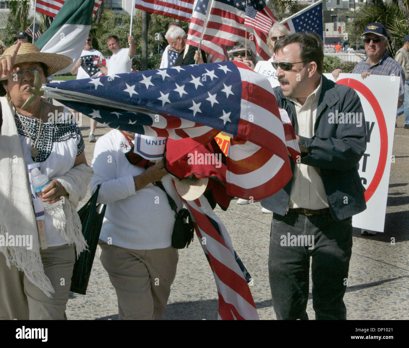 9. April 2006; San Diego, CA, USA; OHN WILSON von Pacific Beach, Recht, verwendet ein Anti-Immigrant Rechte Anhänger, rechts eine amerikanische Flagge, um den Weg einer Frau zu blockieren, die in der Marsch für Einwanderer Rechte von Balboa Park an die Kreisverwaltung teilgenommen hatten aufbauend auf Pacific Highway. WILSON war verärgert, als er sah die amerikanische Flagge, die sie auf den Kopf mit einem kleinen Por trug Stockfoto