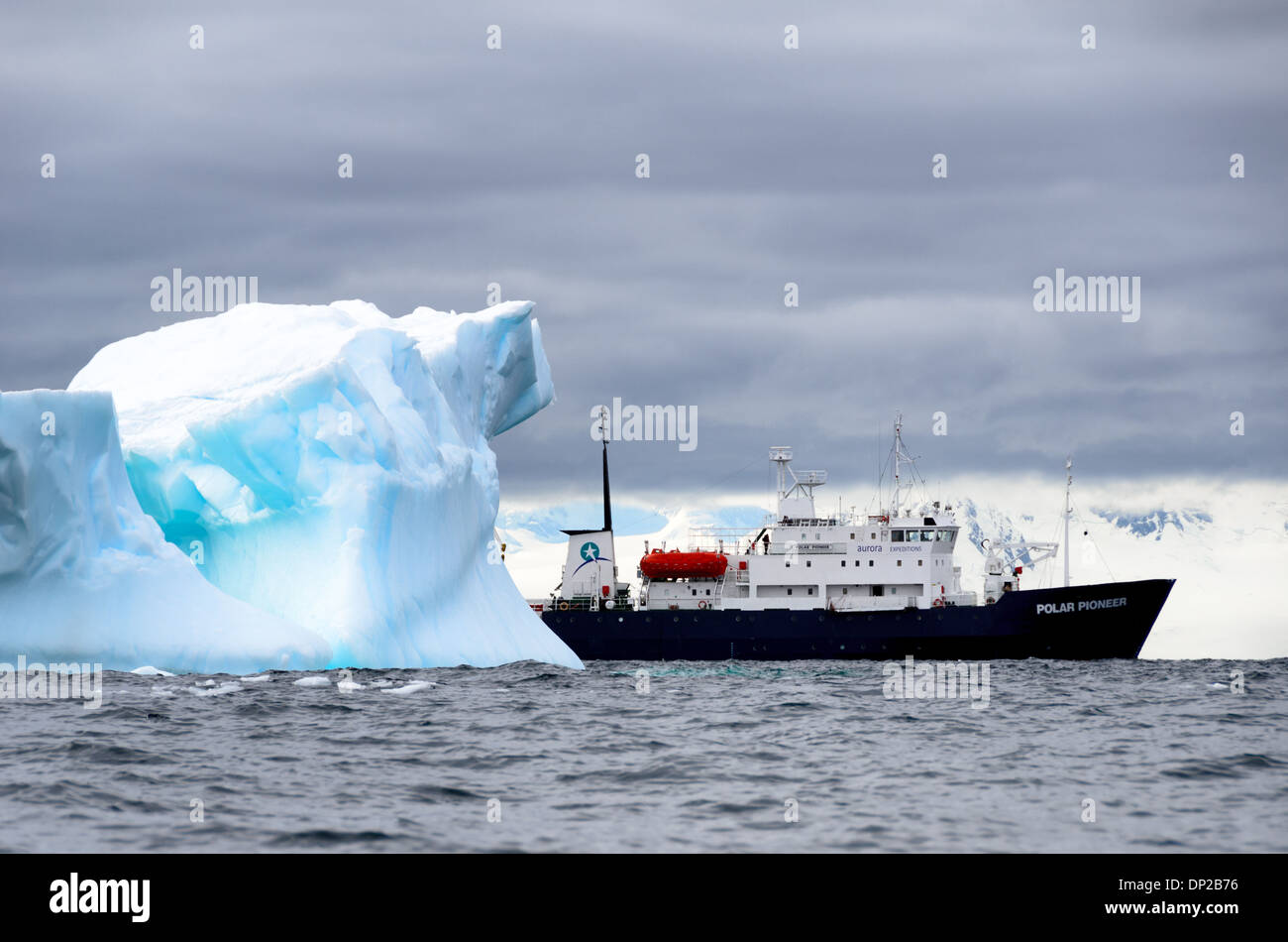 Antarktis - der Antarktis Kreuzfahrt Schiff läuft in ruhigem Wasser hinter einem Eisberg in der Nähe von zwei hummock Insel an der Westküste der Antarktischen Halbinsel. Das Schiff, die Polar Pioneer, ist ein russisches Schiff von Aurora Expeditions betrieben. Stockfoto