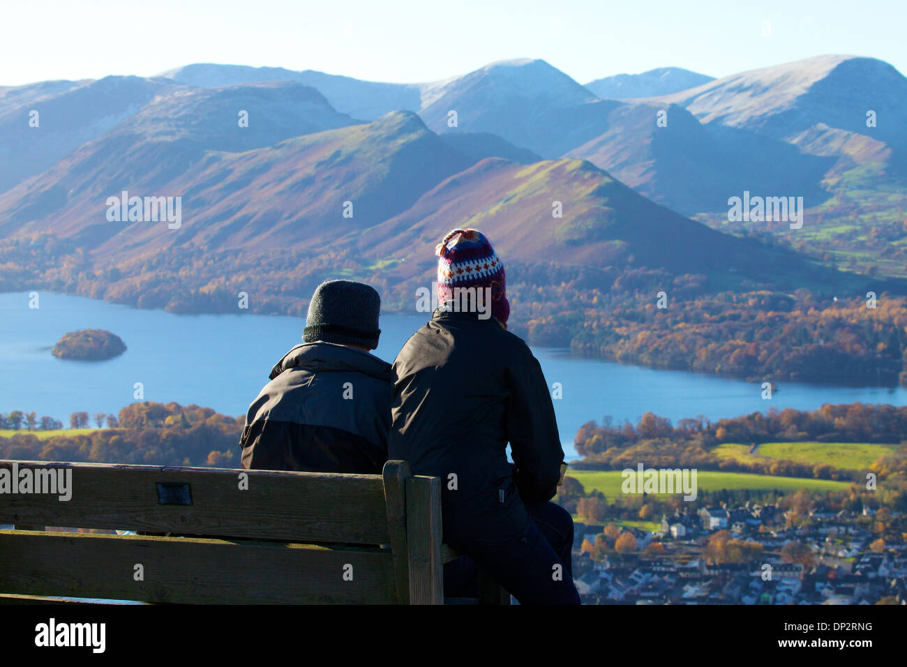 Junges Paar von Wanderer sitzen auf einer Bank über Derwent Water im Lake District National Park mit den Fjälls hinter Stockfoto