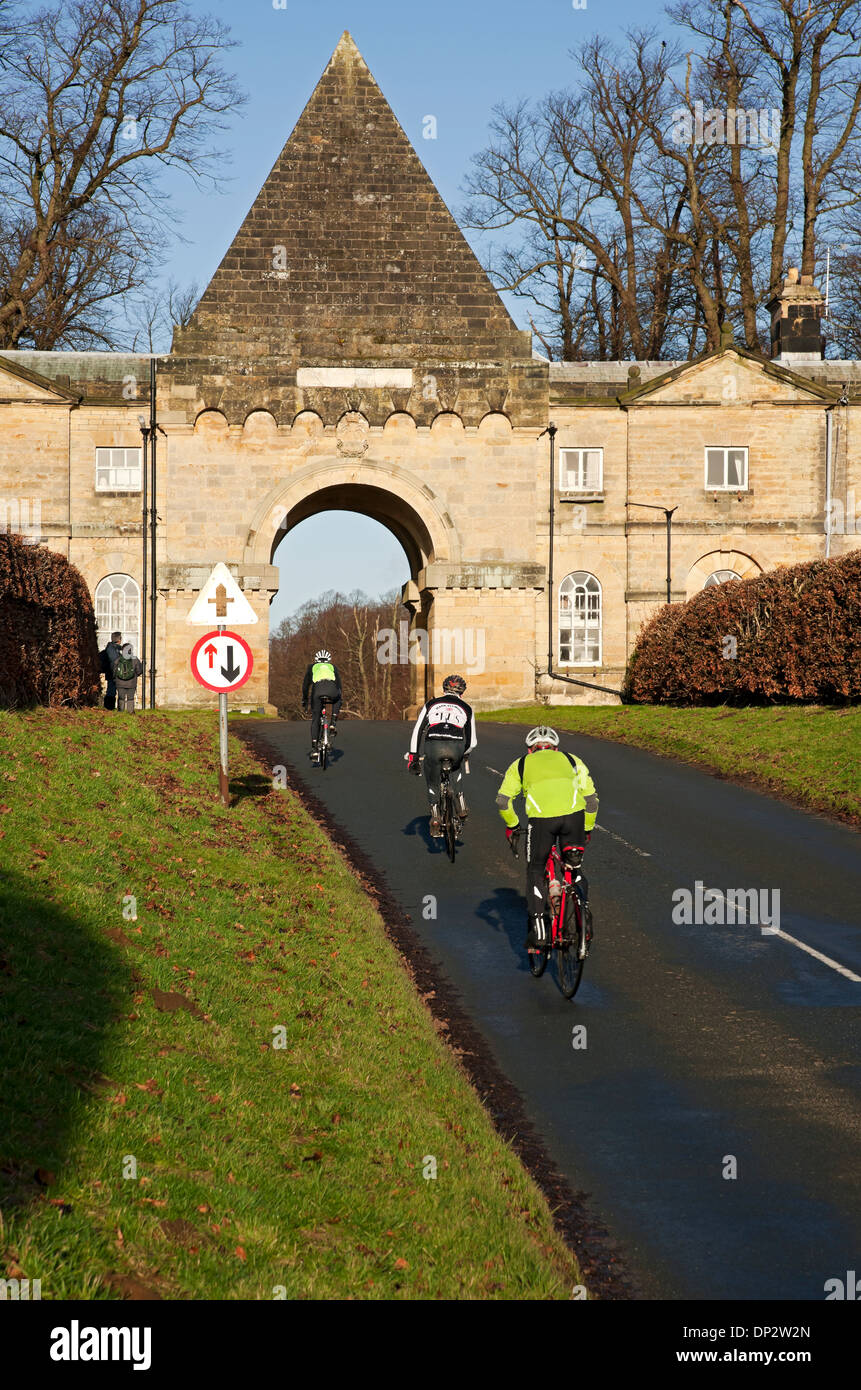 Männer Radler Radfahrer Radfahrer durch Torhaus Bogen in der Nähe von Schloss Howard im Winter North Yorkshire England Großbritannien GB Großbritannien Stockfoto