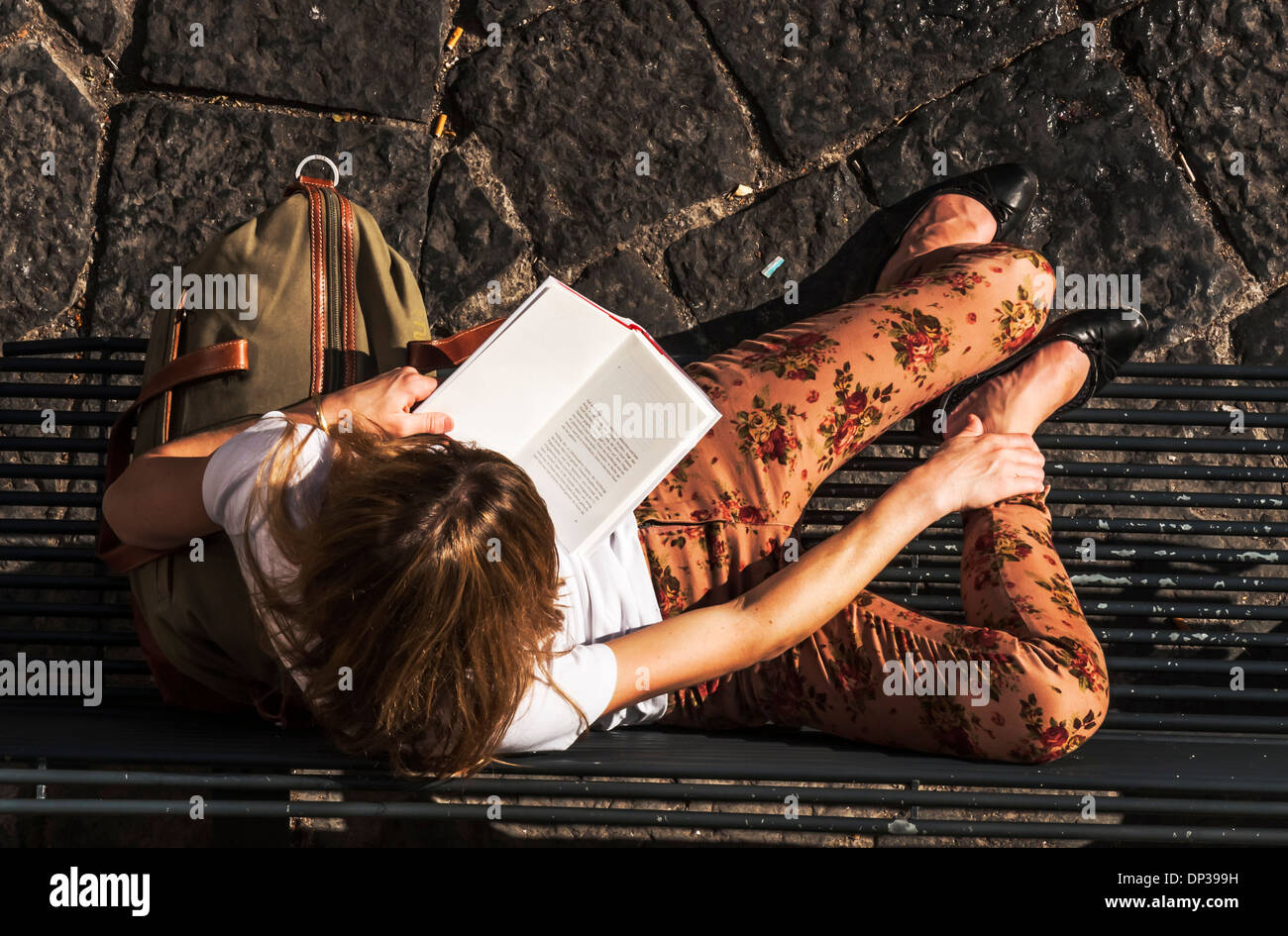 eine Frau liest ein Buch auf einer Bank Stockfoto