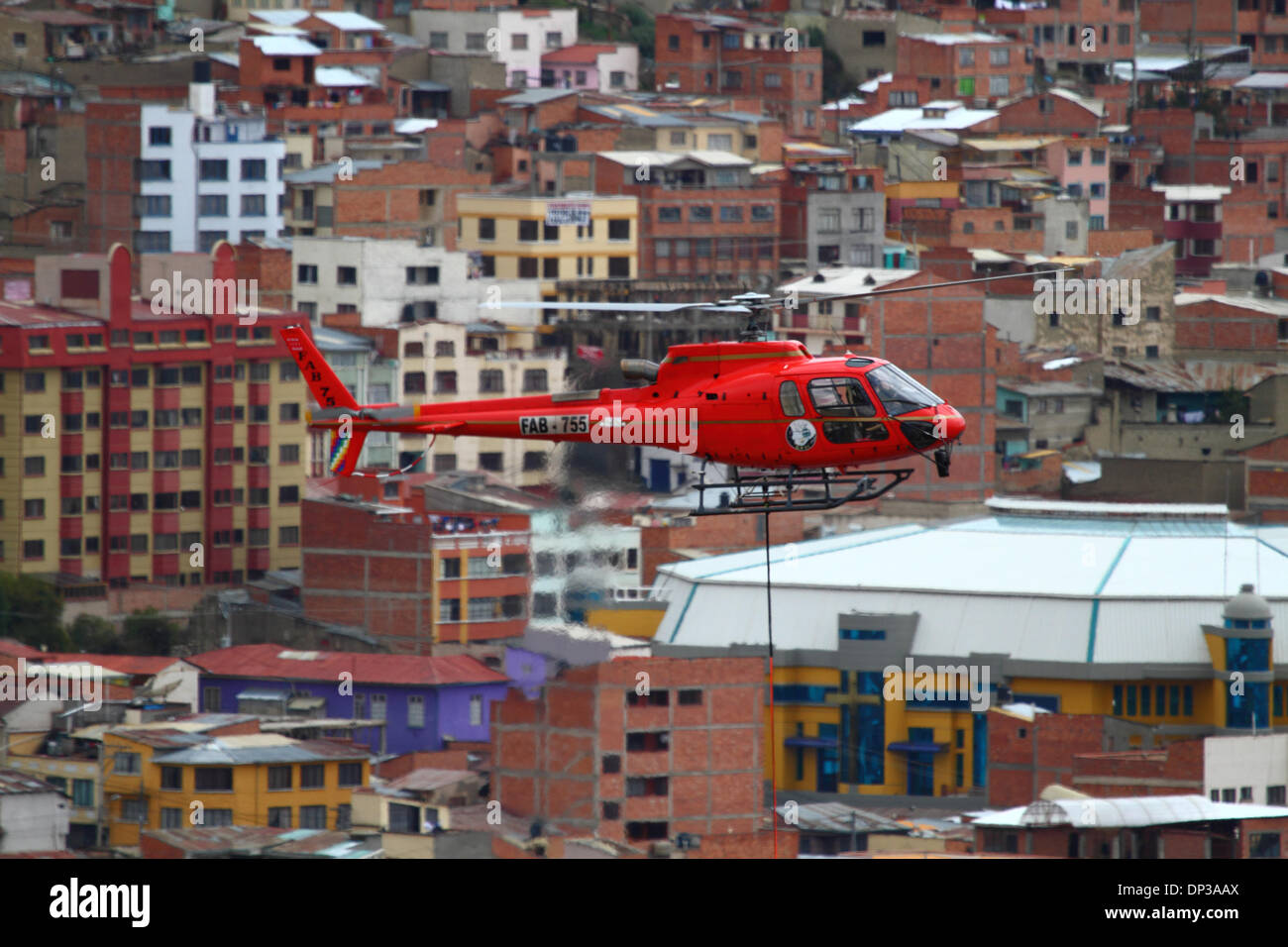 La Paz, Bolivien. 7. Januar 2014. Eurocopter AS 350 B3 Ecureuil Helikopter gehören zu den bolivianischen Luftwaffe (FAB) trägt ein synthetisches Lichtkabel zwischen den Pylonen, der erste Teil des Prozesses der endgültigen Stahlseil zu installieren, die die Gondeln für die neue Seilbahn führt / Gondelbahn, die derzeit im Bau, die Städte La Paz und El Alto zu verknüpfen. Drei separate Seilbahn, die Linien sind geplant als Teil eines ehrgeizigen Projekts, Verkehrsstaus, mit der ersten Zeile aufgrund zu lindern bis März 2014 abgeschlossen sein. Stockfoto