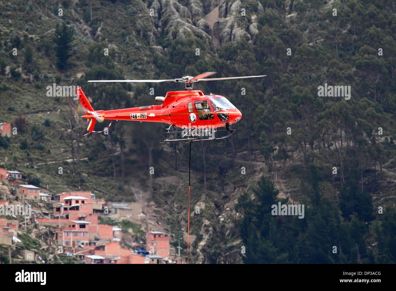 La Paz, Bolivien. 7. Januar 2014. Eurocopter AS 350 B3 Ecureuil Helikopter gehören zu den bolivianischen Luftwaffe (FAB) trägt ein synthetisches Lichtkabel zwischen den Pylonen, der erste Teil des Prozesses der endgültigen Stahlseil zu installieren, die die Gondeln für die neue Seilbahn führt / Gondelbahn, die derzeit im Bau, die Städte La Paz und El Alto zu verknüpfen. Drei separate Seilbahn, die Linien sind geplant als Teil eines ehrgeizigen Projekts, Verkehrsstaus, mit der ersten Zeile aufgrund zu lindern bis März 2014 abgeschlossen sein. Stockfoto