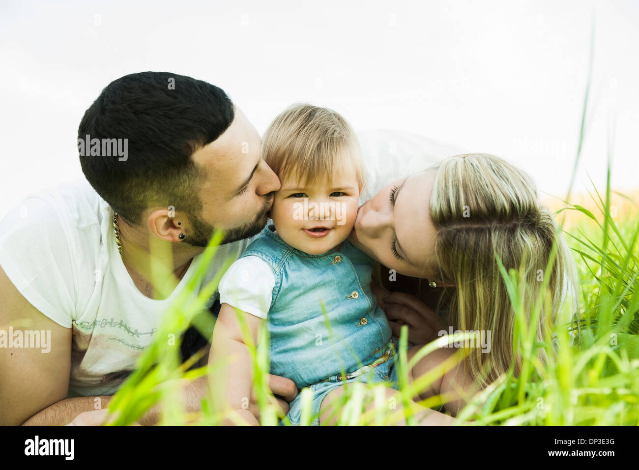 Porträt von Mutter und Vater küssen Baby Tochter Wangen, Mannheim, Baden-Württemberg, Deutschland Stockfoto