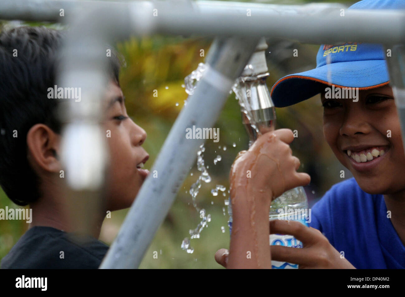 20. Juli 2006; Ciamis, West-Java, Indonesien; Kinder wohnen im Flüchtlingszentrum in den Hügeln von Pangandaran, füllen West-Java glücklich ihre Trinkflaschen mit sauberem Wasser. Die Dorfbewohner, die den Tsunami überlebt noch kümmern über die Möglichkeiten eines anderen Erdbeben und Tsunami. Ein Tsunami in der Küste der indonesischen Insel Java töten mehr als 550 Menschen, ove Stockfoto