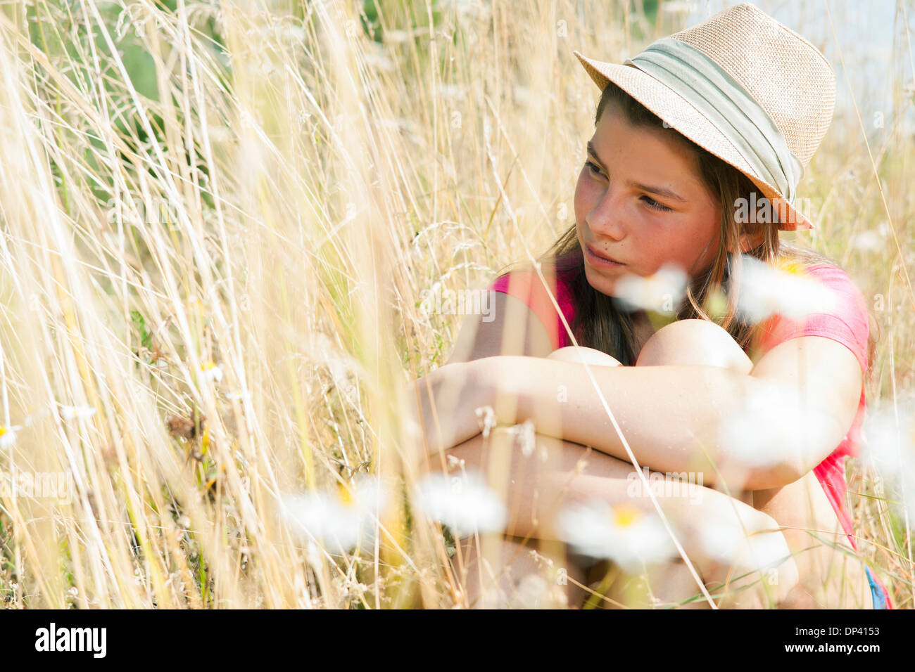 Porträt von Mädchen mit Hut, sitzen im Feld, Deutschland Stockfoto