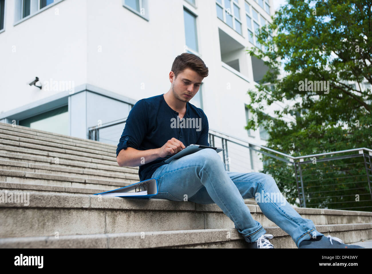 Junger Mann sitzt auf Schritte im Freien, mit Tablet-PC, Deutschland Stockfoto