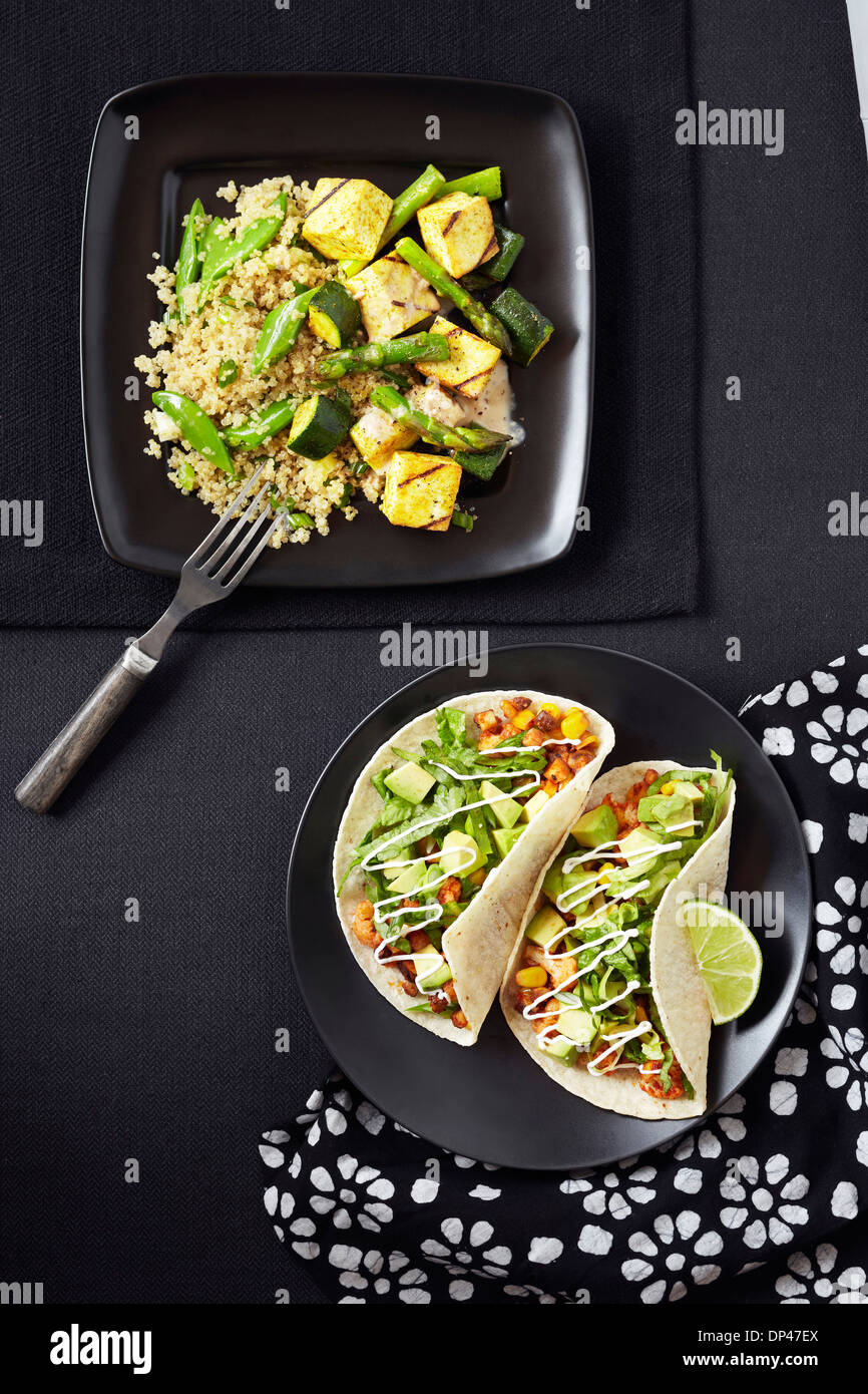 Draufsicht auf Quinoa mit Zucchini, Spargel und Tofu und Tacos mit Bohnen-Mix und Avocado, Studioaufnahme Stockfoto