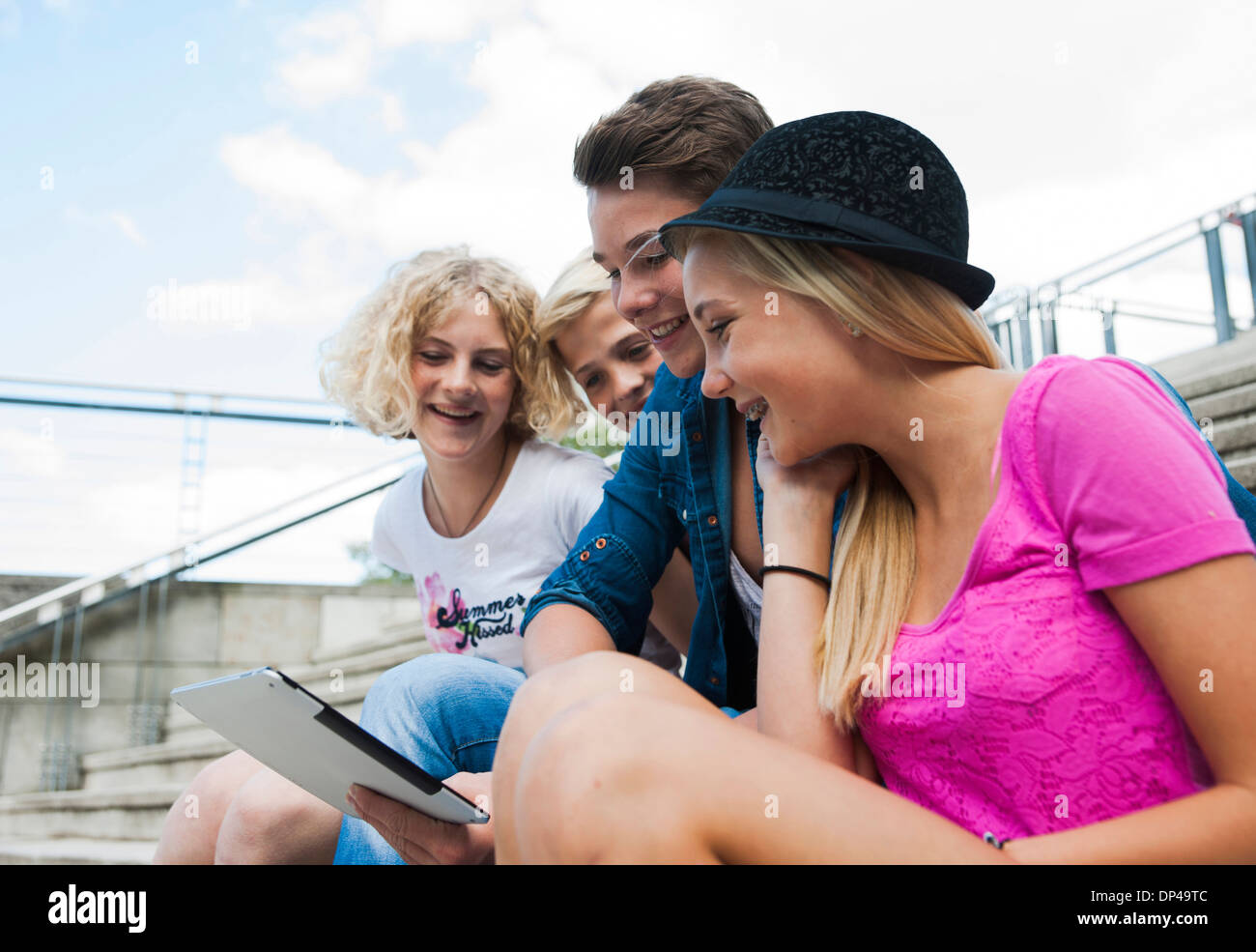 Gruppe von Jugendlichen sitzen auf Treppen im freien Blick auf Tablet-PC, Deutschland Stockfoto