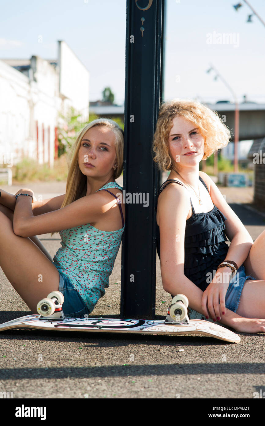 Porträt von Mädchen im Teenageralter im Freien mit Skateboard, Blick in die Kamera, sitzen auf der Straße, Deutschland Stockfoto