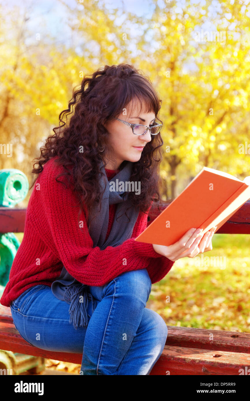 Mädchen Lesen eines Buches im Herbst park Stockfoto