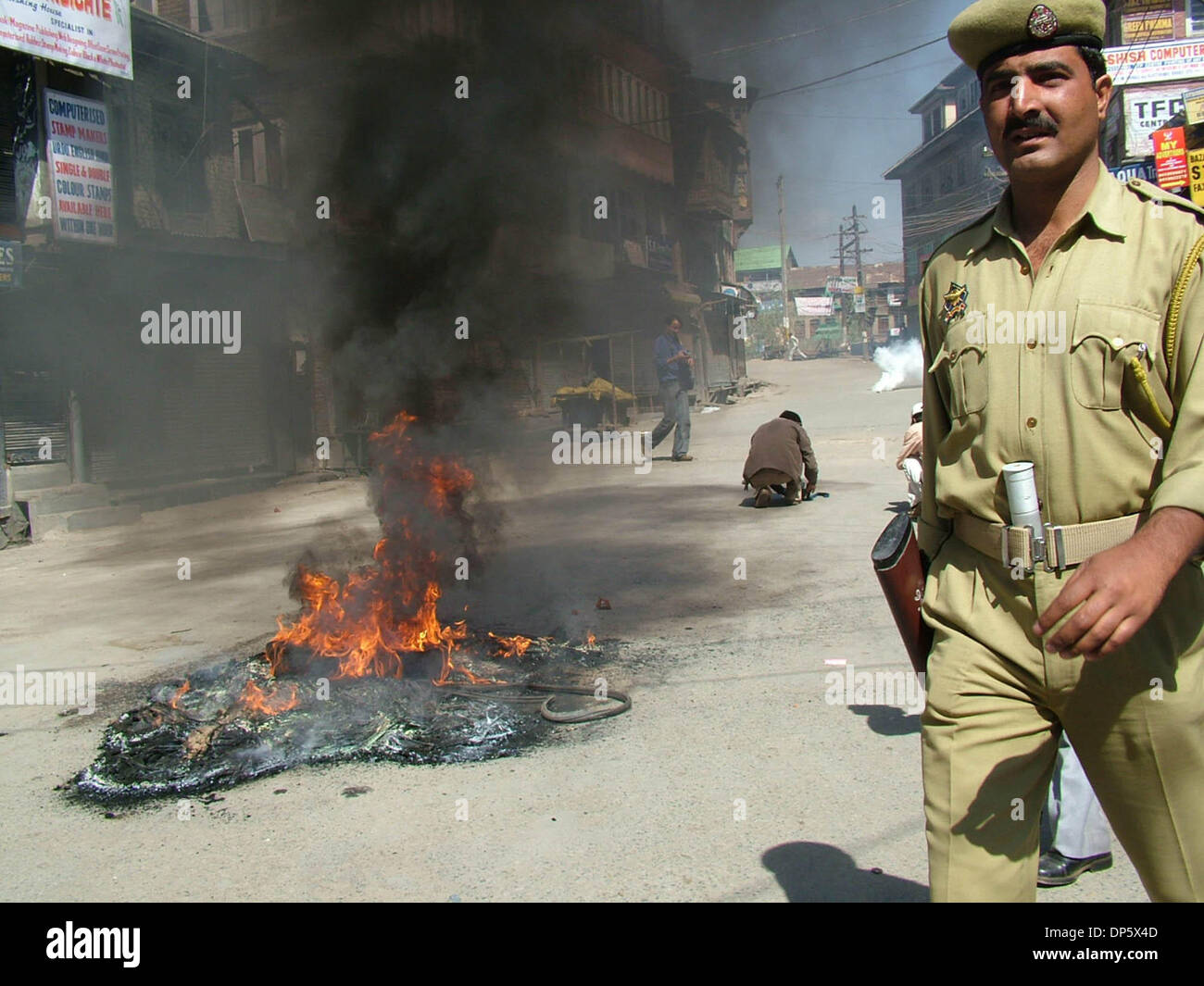 Sep 27, 2006; Srinagar, Kaschmir, Indien; Ein Polizist kommt vorbei, wie Demonstranten verbrennen Reifen in Srinagar, Sommer in der Hauptstadt des indischen verabreicht Kaschmir. Kaschmir ist ausgebrochen, an den Protesten am Mittwoch, nachdem ein indisches Gericht zum Tode verurteilt, Afzal Guroo, ein Geschäftsmann, der Kashmiri ausgesprochen für den Angriff auf das indische Parlament im Dezember 2001 beteiligt. Obligatorische Credit: Foto von Alta Stockfoto